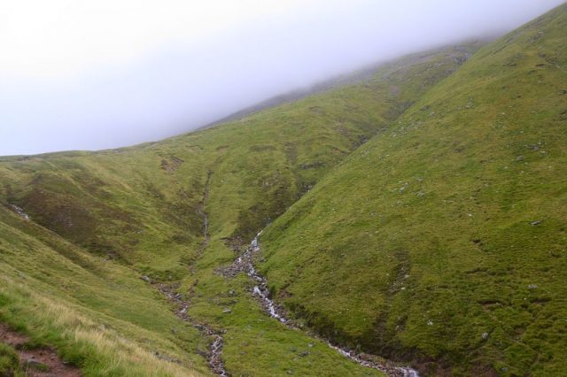 Sedlo mezi Meall an t-Suidhe a Ben Nevis, v pozadí cesta na Ben Nevis zahalená mlhou.